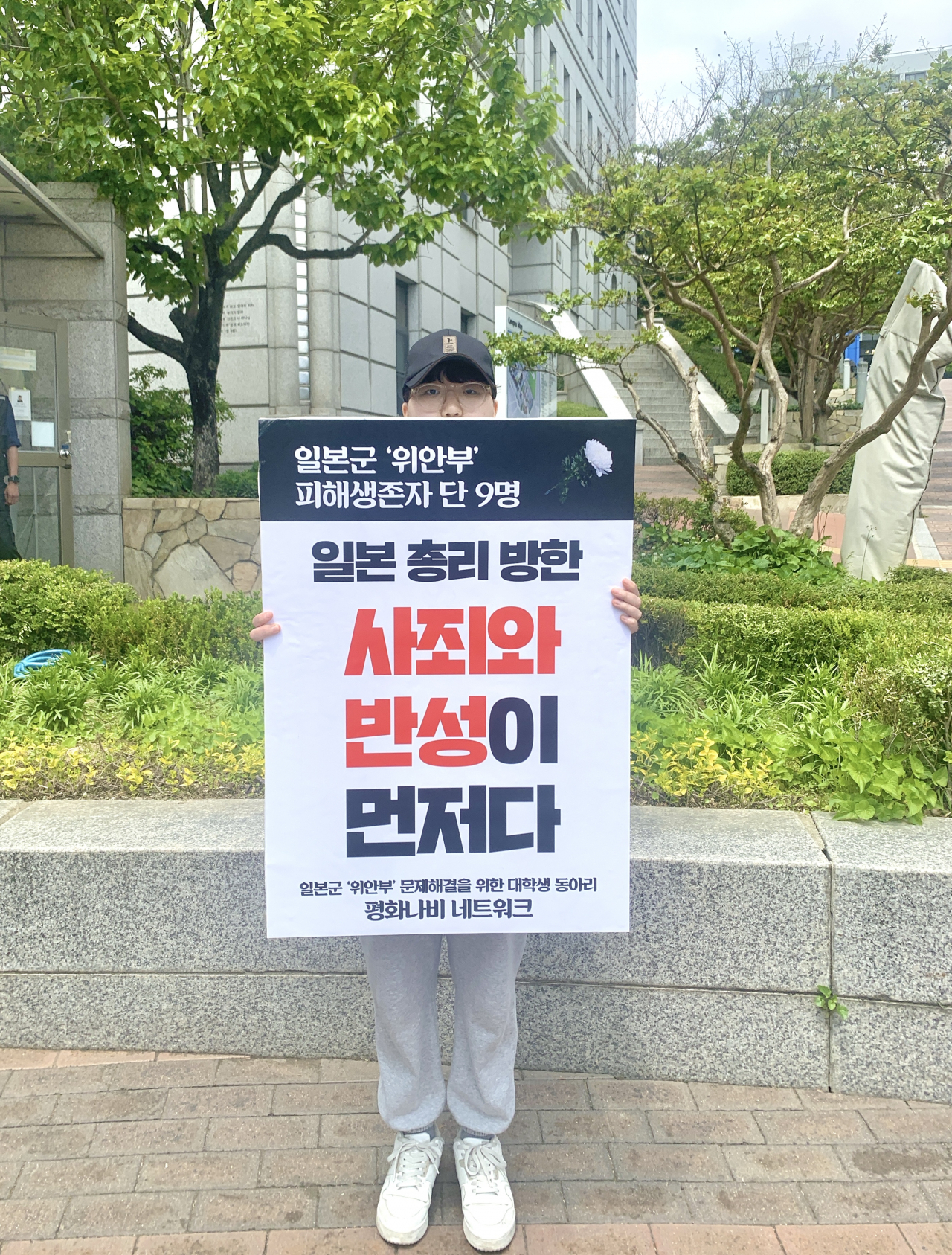 Jang Ji-won, a civic activist under the Peace Butterfly Network and a 19-year-old student majoring in law at Sookmyung Women’s University, stages a one-person rally at her school campus on Thursday while holding a banner that reads, “Apology and reflecting on the past should come first before Japanese Prime Minister’s visit (to Korea).” (No Kyung-min/The Korea Herald)