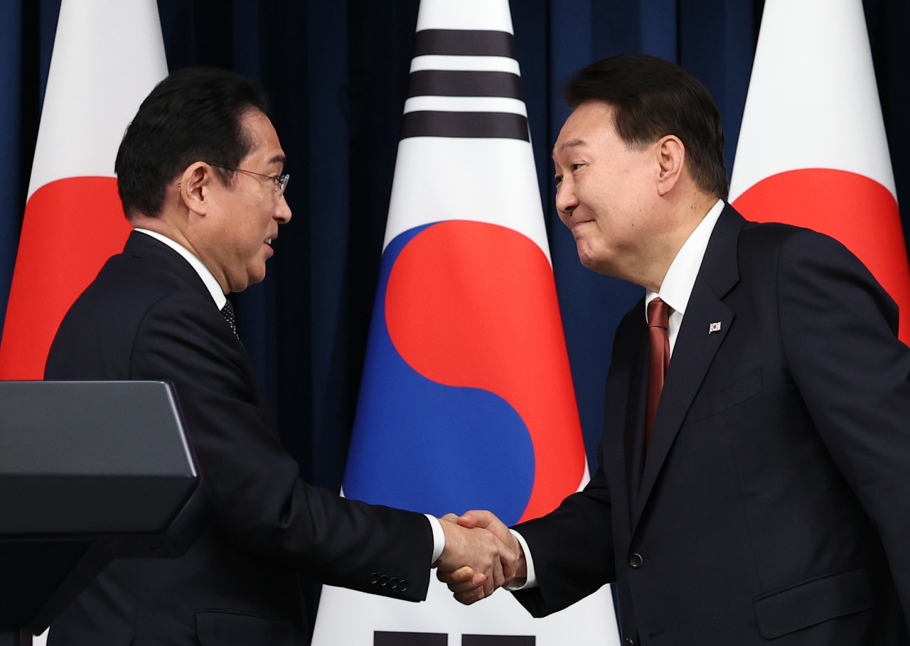 South Korean President Yoon Suk Yeol (right) and Japanese Prime Minister Fumio Kishida are seen in this photo shaking hands after holding a joint press conference at the presidential office in Seoul on Sunday. During their talks, Yoon and Kishida agreed to allow a group of South Korean experts to visit Japan to inspect the planned release of radioactive water from the crippled Fukushima nuclear power plant. (Yonhap)