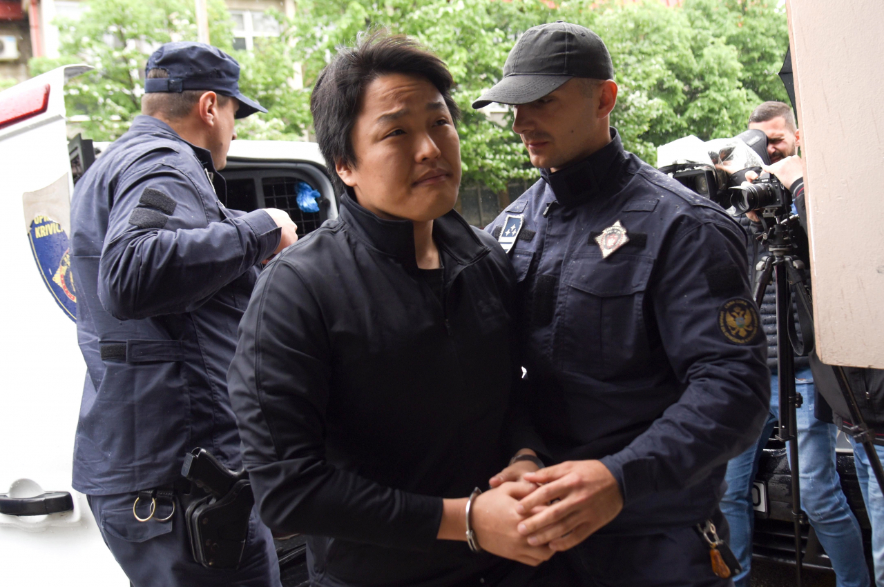 Police officers escort South Korean crypto mogul Do Kwon (C) in Podgorica, Montenegro on Thursday. Do Kwon, who is on trial in Montenegro for forging travel documents, is wanted in South Korea, Singapore and the US for the involvement in the collapse of his company Terraform, which is estimated to have cost investors more than 40 billion US dollars. (Photo - EPA)