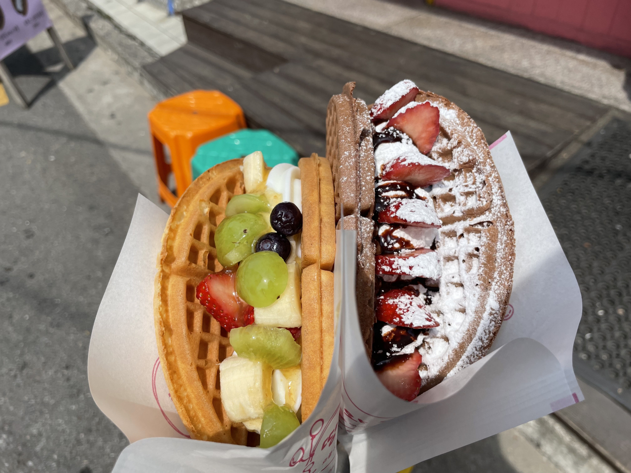Ddingddong Waffle's signature plain waffle with yogurt ice cream and fruit (left) and cacao waffle with strawberries and chocolate sauce (right). (Kim Da-sol/The Korea Herald)