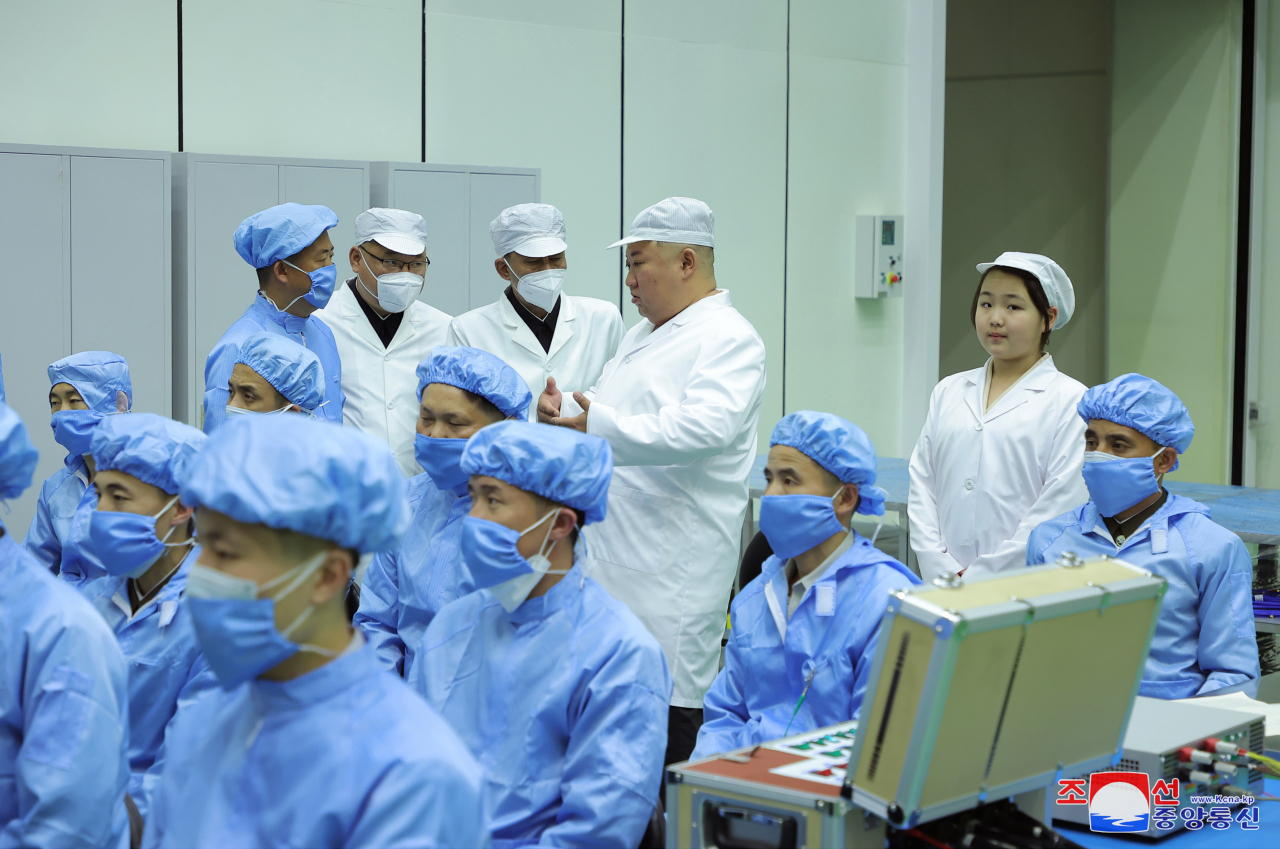 North Korean leader Kim Jong-un (second from right, rear), along with his daughter Ju-ae (far right, rear), talks with members of the Non-permanent Satellite Launch Preparatory Committee in Pyongyang on Tuesday to inspect the country's first military reconnaissance satellite. Kim gave the green light for its 