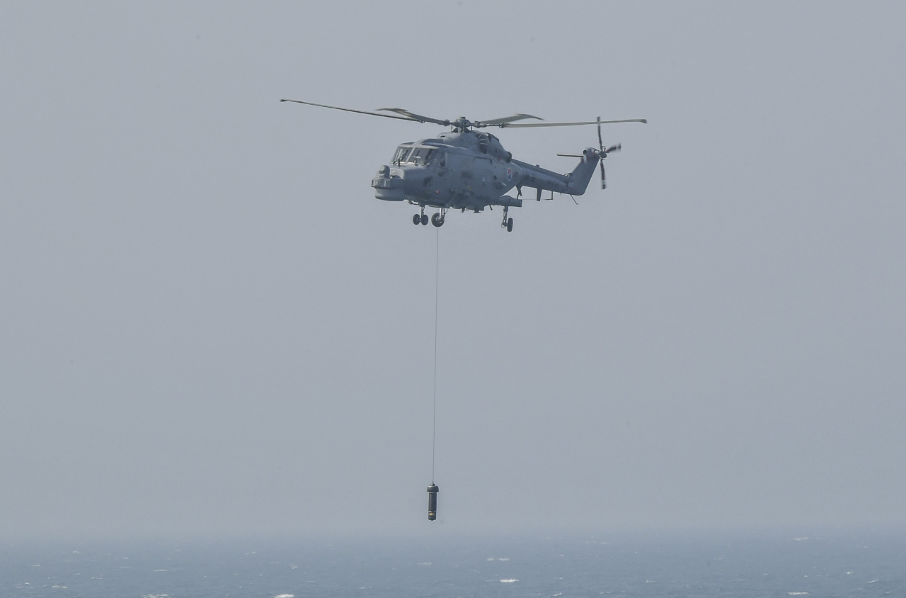 The Lynx helicopter deploys a dipping sonar that can dive down below the sea surface and detect targets upon reaching the designated point during an anti-submarine warfare staged on Tuesday in waters off the island of Gadeokdo in Busan. (Republic of Korea Navy)