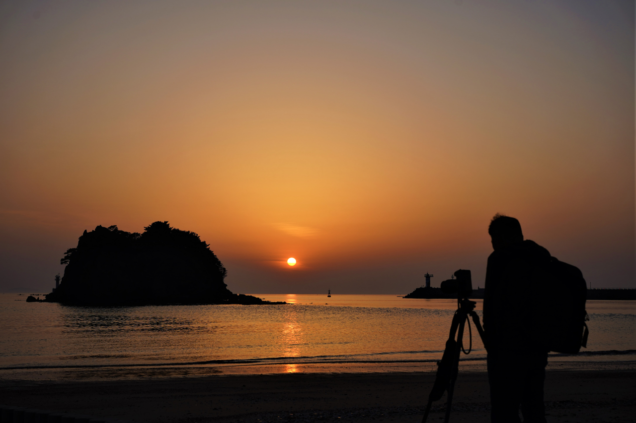 A photographer takes a sunset picture at Kkotji Beach on May 9. (Lee Si-jin/The Korea Herald)