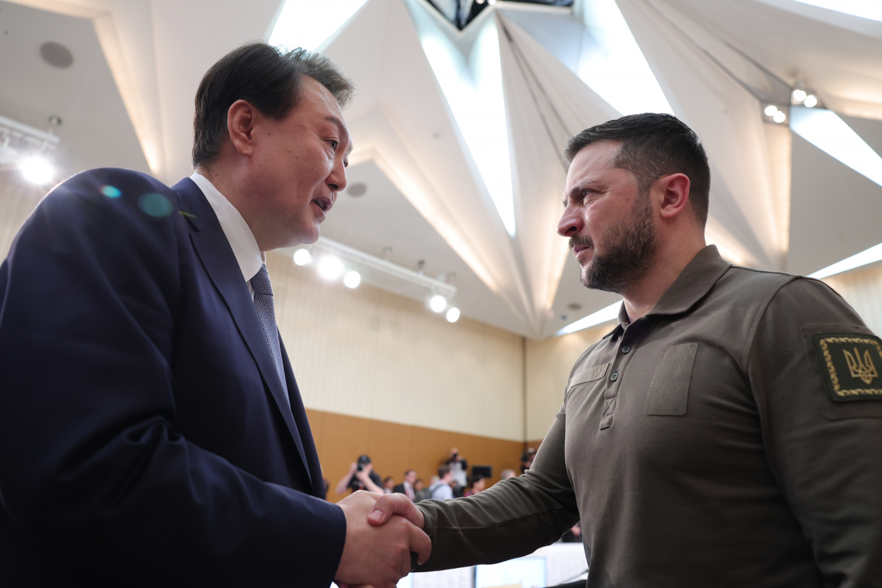 South Korean President Yoon Suk Yeol (left) shakes hands with Ukrainian President Volodymyr Zelenskyy at an expanded Group of Seven summit session on Sunday in Hiroshima, Japan. (Yonhap)