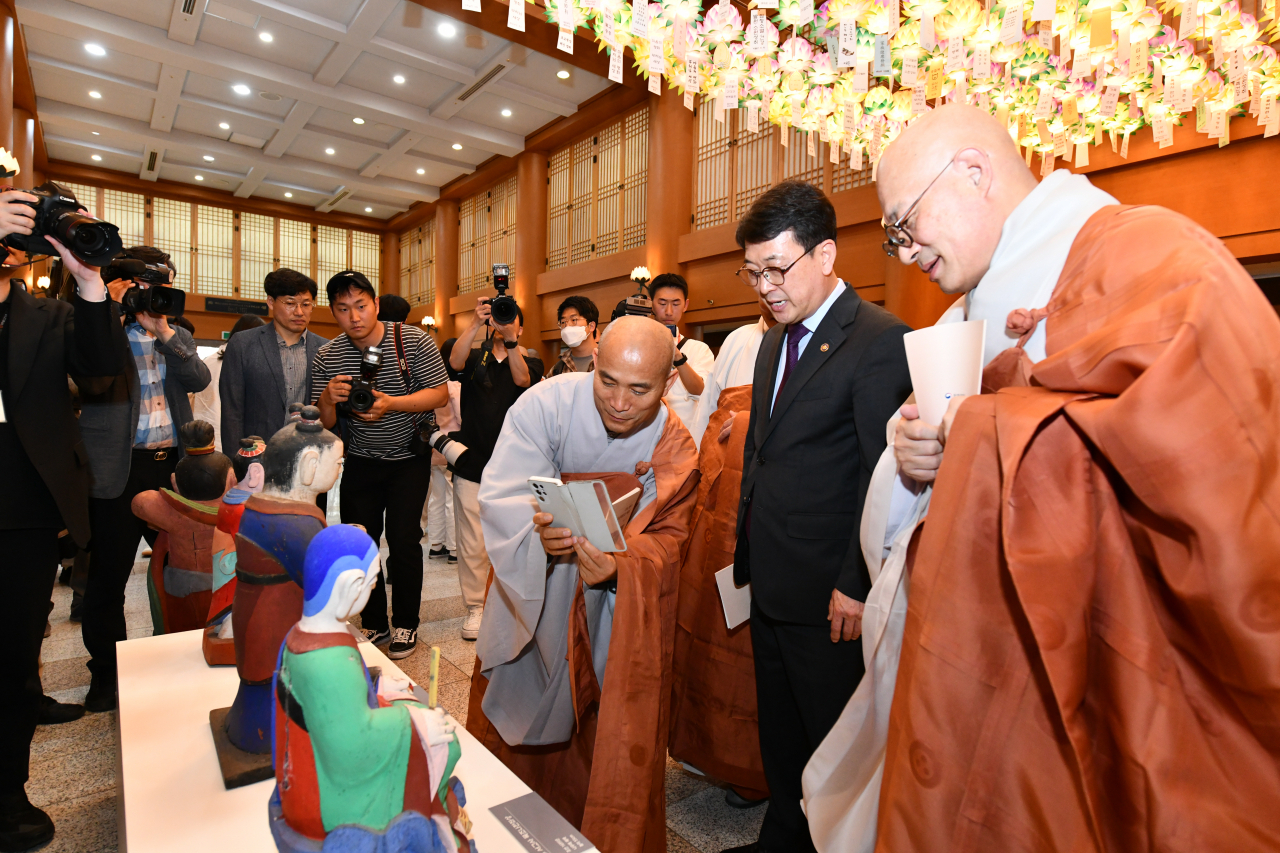 The Ven. Jinwoo (right), president of the Jogye Order of Korean Buddhism, and Choi Eung-chon (second from right), the head of the Cultural Heritage Administration, looks at one of the returned statues at the Korean Buddhism History and Culture Memorial Hall in central Seoul, Tuesday. (CHA)