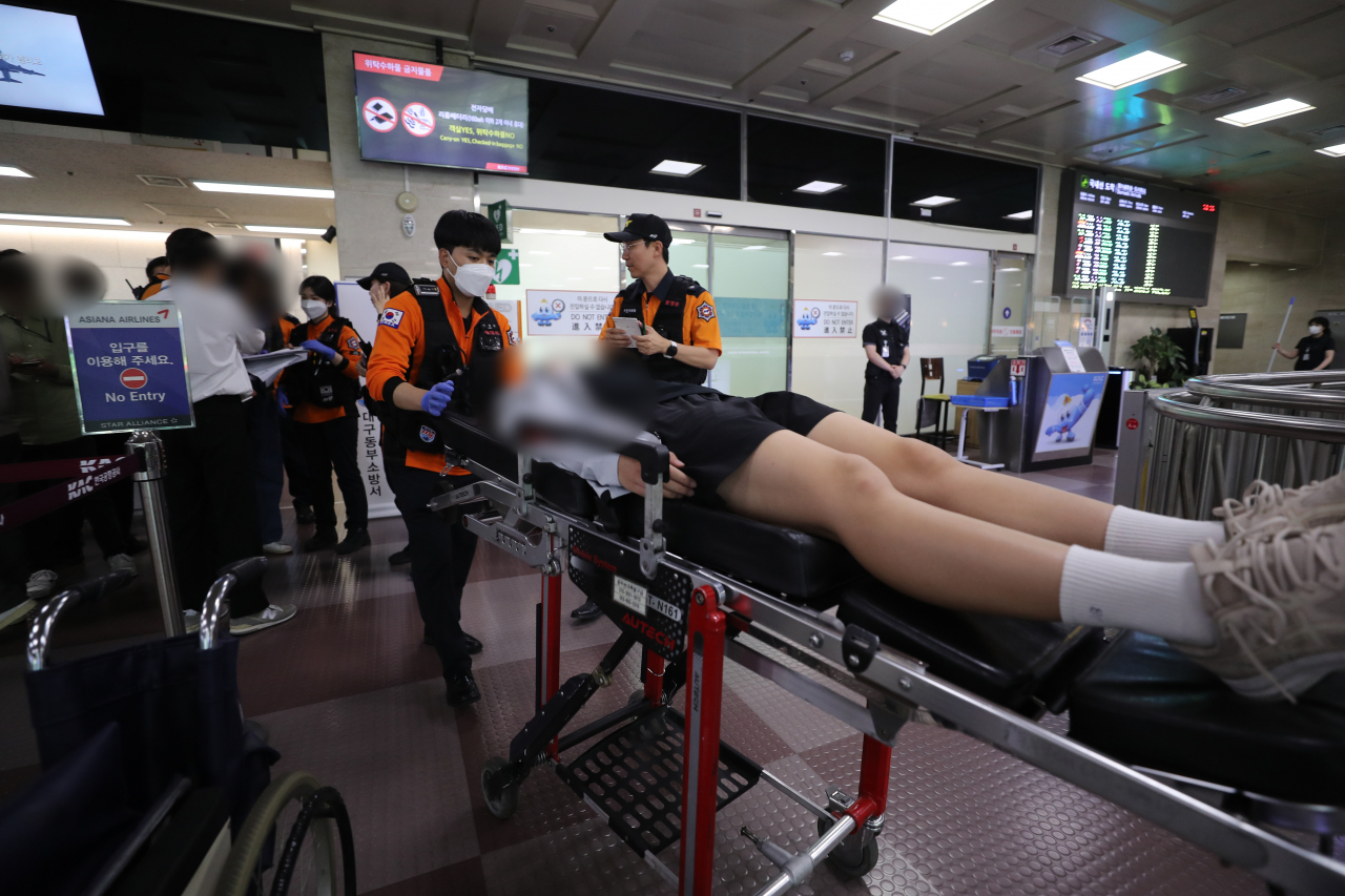 This photo shows one of 194 passengers carried on a stretcher after an airplane landed with its door open at around 12:45 p.m. Friday. (Yonhap)