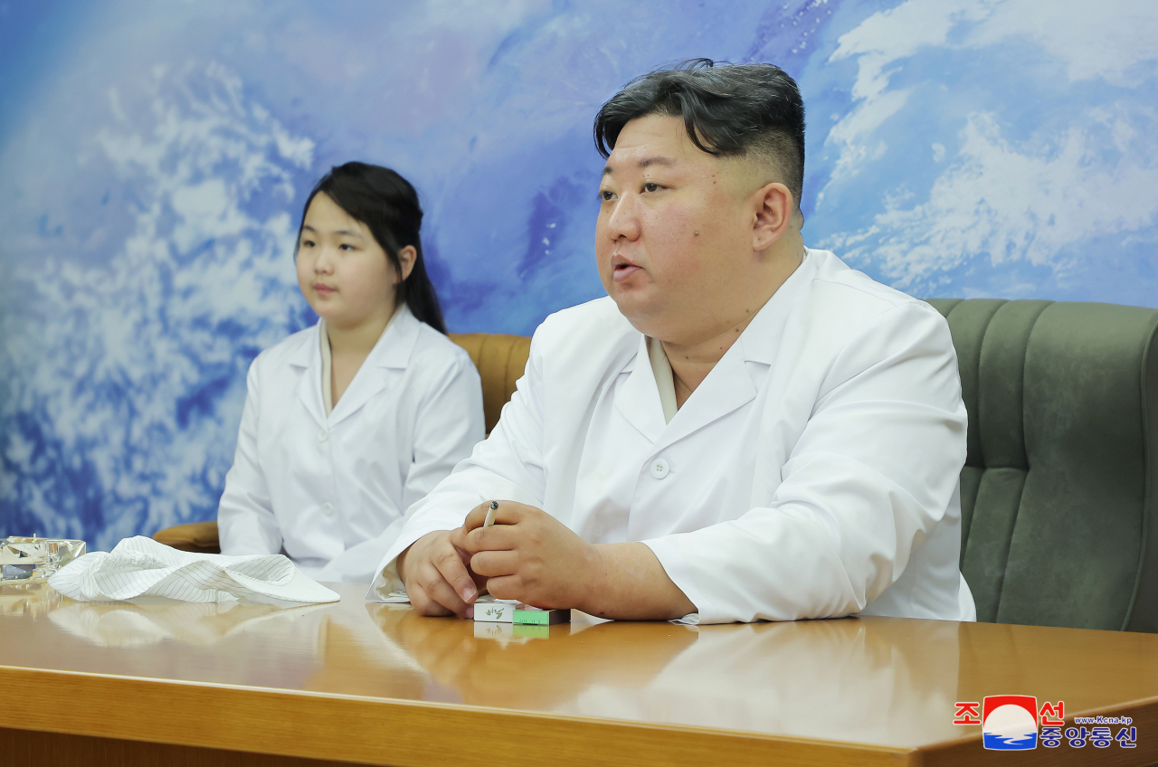 North Korean leader Kim Jong-un (right), along with his daughter Ju-ae, is pictured as he meets with members of the Non-permanent Satellite Launch Preparatory Committee in Pyongyang on May 16, to inspect the country's first military reconnaissance satellite, in this file photo. (KCNA)