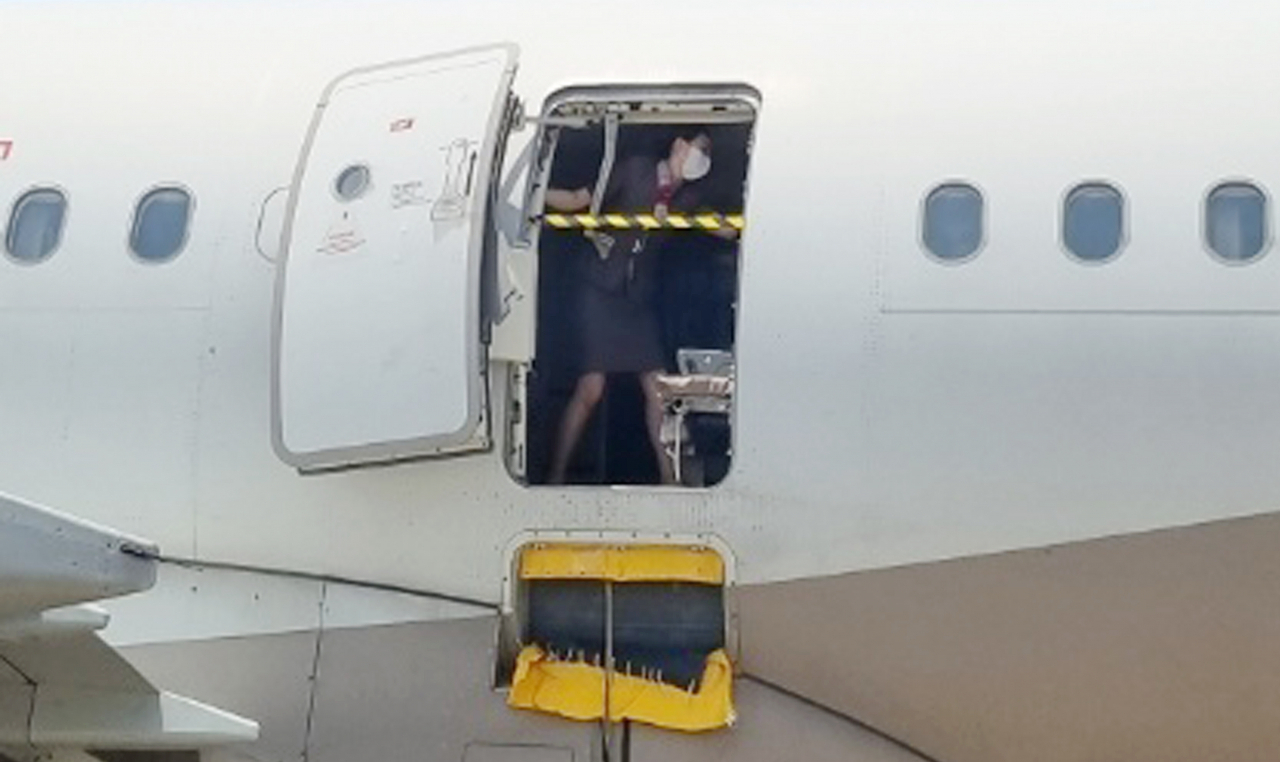 A stewardess mounts a safety bar across the emergency exit of the A321-200 aircraft that opened before landing on Friday. (Yonhap)
