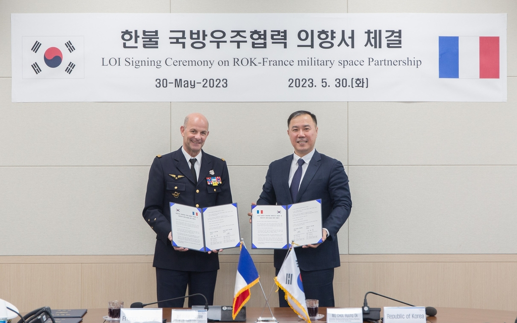 Choi Byung-ok (right), director general at the defense policy bureau of South Korea's defense ministry, and French Space Commander Philippe Adam, pose for a photo after signing a letter of intent on the South Korea-France military space partnership in Seoul on May 30, 2023, in this photo released by the defense ministry. (Yonhap)