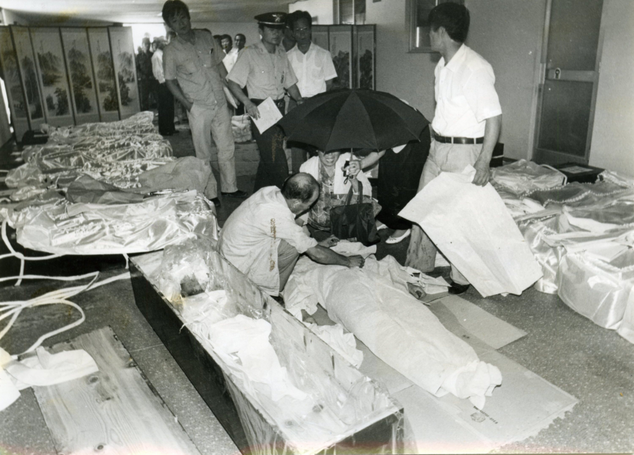 Authorities recover the bodies of those who died in the mass-suicide in this photo taken on Aug. 29, 1987.