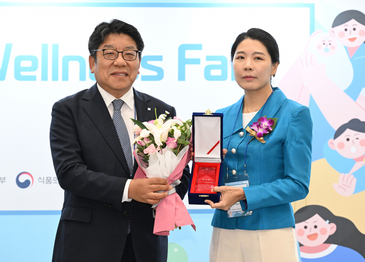 The Korea Herald CEO Choi Jin-young delivers a plaque of appreciation to Shin Hyun-young, a member of the Health and Welfare Committee of the National Assembly, at the 2023 K-wellness fair on Friday. (Im Se-jun/The Korea Herald)