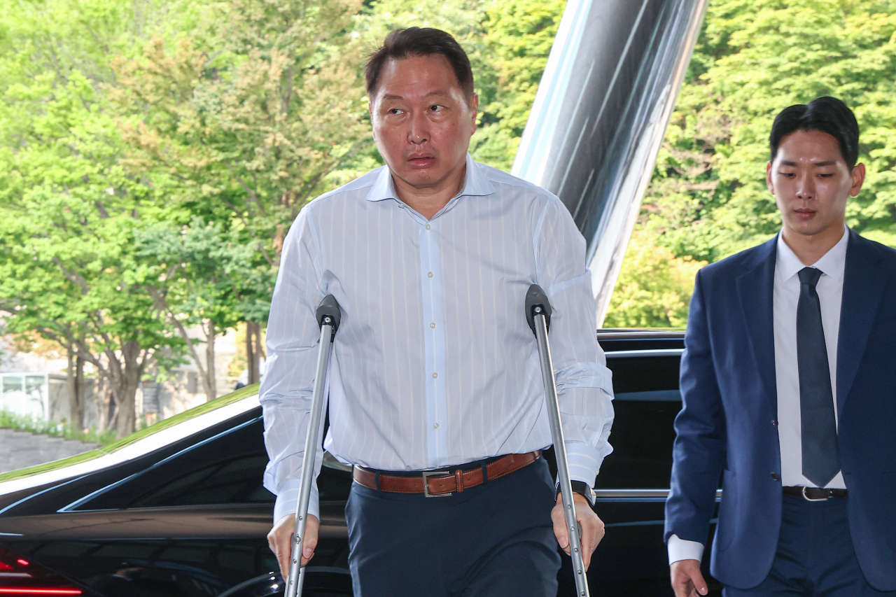 SK Group Chairman Chey Tae-won arrives at a Seoul hotel Thursday to attend the group’s 2023 Extended Management Meeting. He walked on crutches due to a tennis injury. (Yonhap)