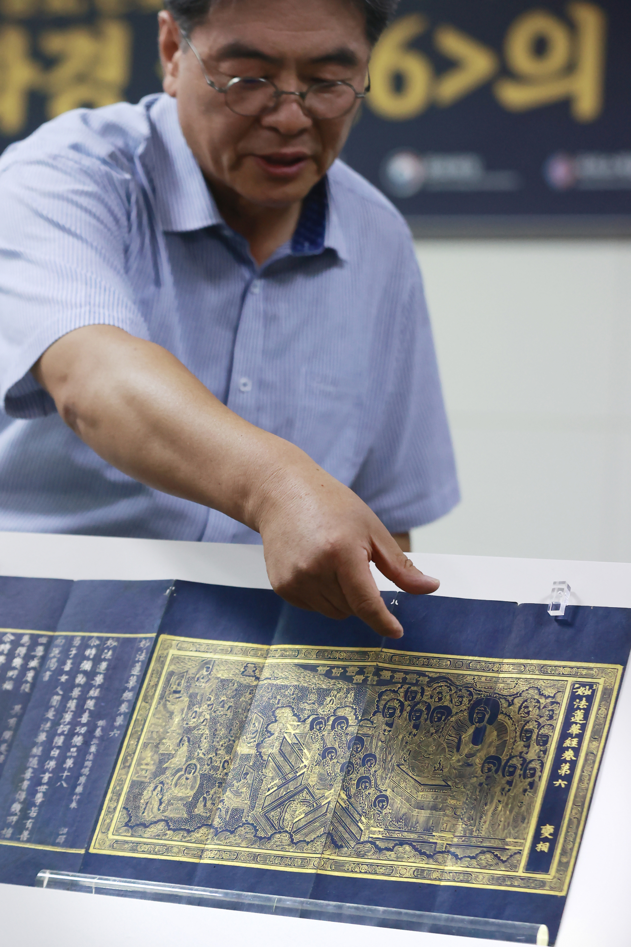 Bae Young-il, director of the Seongbo Museum at Magok Temple, points to an illustration inside Vol. 6 of Saddharmapundarika Sutra, during a press event held at the National Palace Museum of Korea, Thursday. (Yonhap)