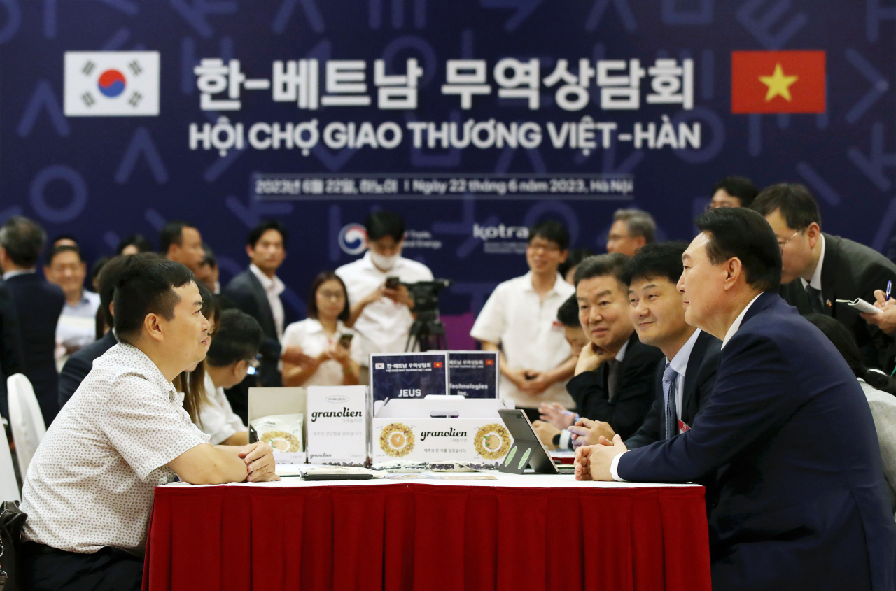 South Korean President Yoon Suk Yeol (right) talks with participants during a South Korea-Vietnam business partnership fair in Hanoi on Thursday. (Yonhap)