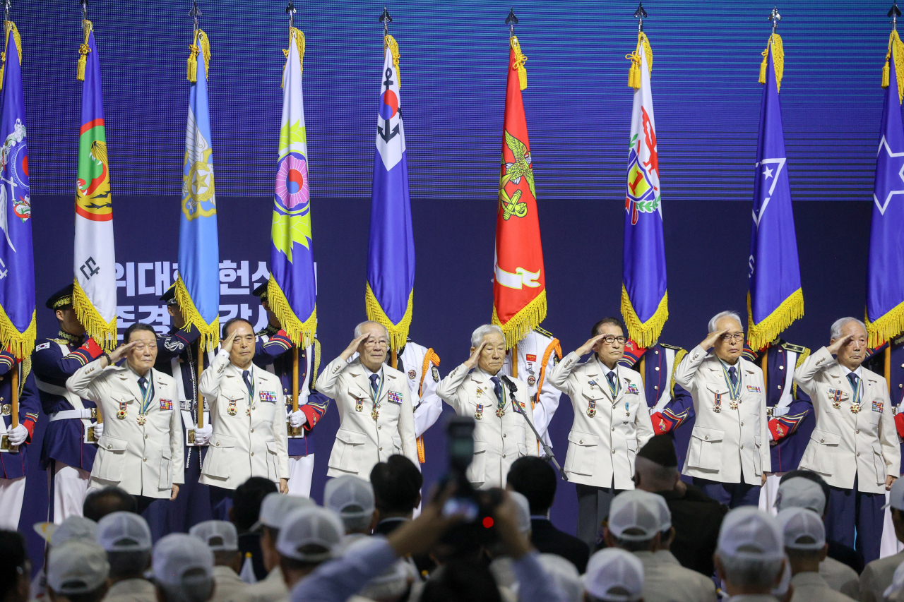 Korean War veterans clad in white uniforms provided by the South Korean government salute in front of participants during a commemorative ceremony held in Seoul on Sunday. (Ministry of Patriots and Veterans Affairs)