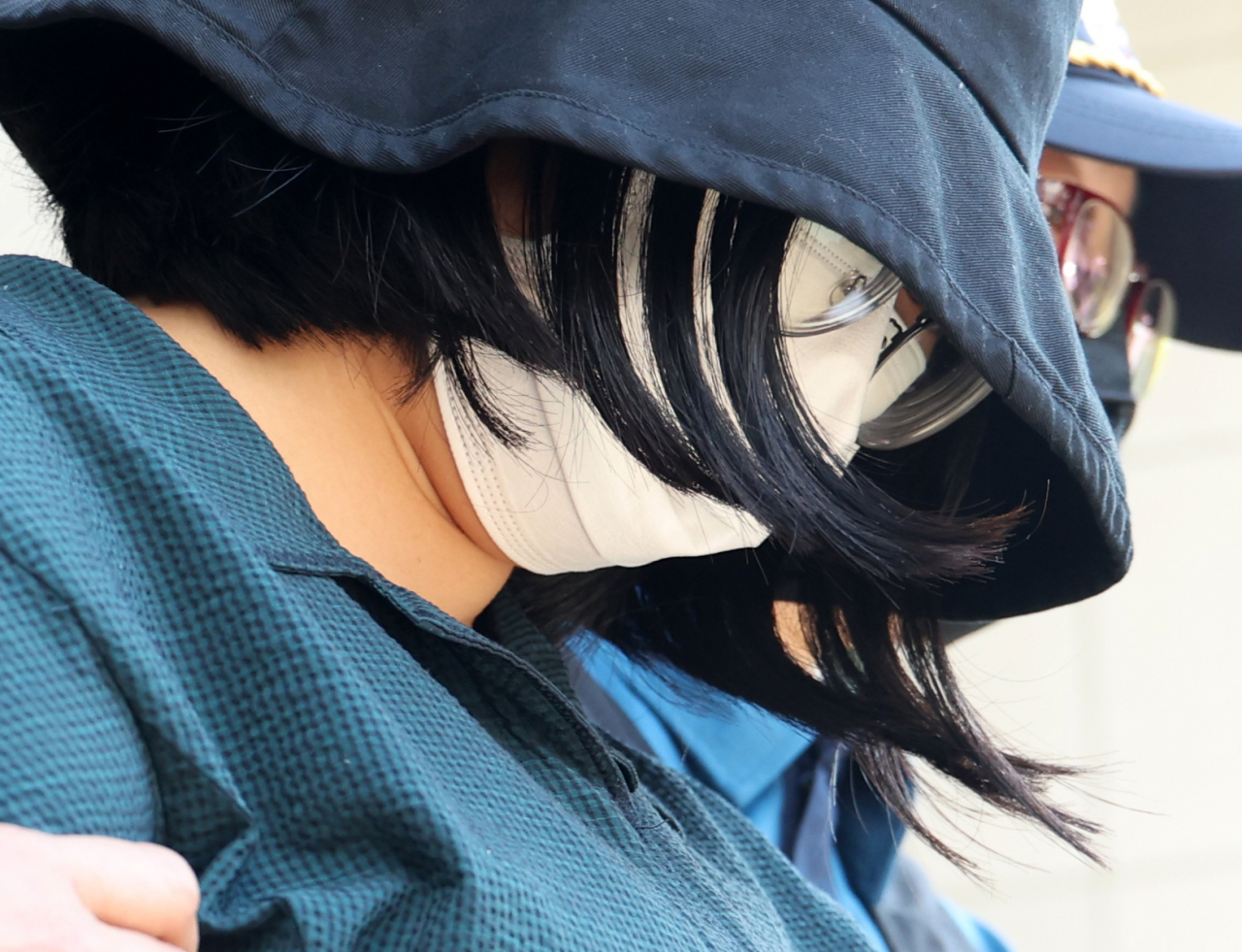 Murder suspect Jung Yoo-jung, wearing a hat and a mask, leaves a police detention center to be taken to the prosecutors office in Busan on June 2. (Yonhap)