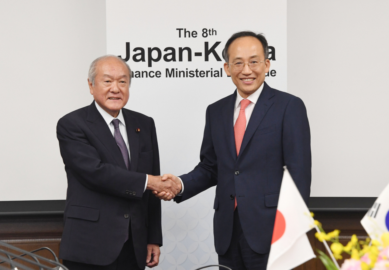 Korea's Finance Minister Choo Kyung-ho (right) shakes hand with his Japanese counterpart Shunichi Suzuki after holding a talk in Tokyo on Thursday. It was the first time in seven years for the two top finance heads to meet an official one-on-one talk. (Finance Ministry)