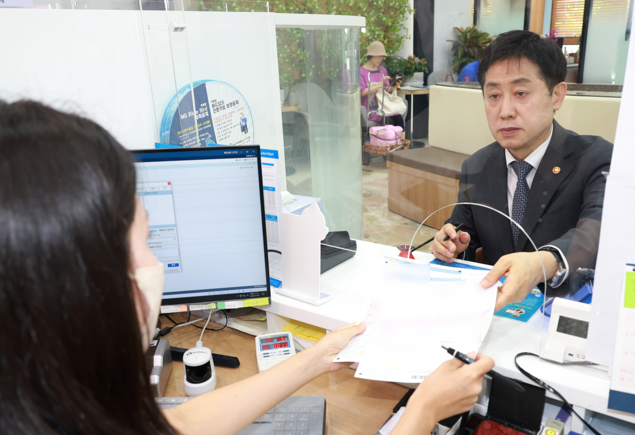 Financial Services Commission Chairman Kim Joo-hyun deposits 60 million won ($46,000) at a Seoul branch of the Korean Federation of Community Credit Cooperatives on Friday amid growing concerns about the bank’s financial soundness. (Yonhap)