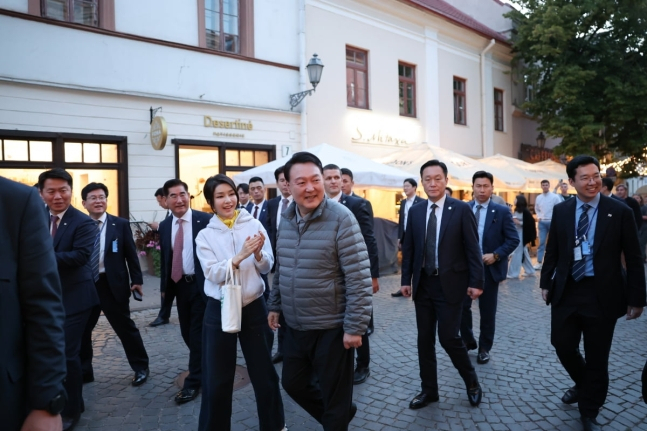 President Yoon Suk Yeol and first lady Kim Keon Hee takes a walk in the old town area of Vilnius on Monday evening. (Yonhap)