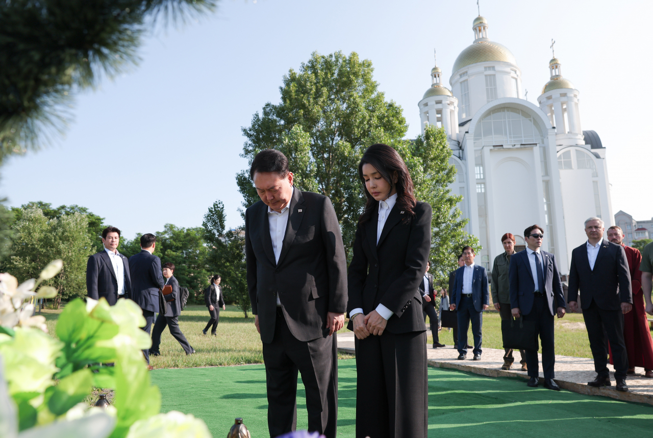 President Yoon Suk Yeol and first lady Kim Keon Hee, who made a surprise visit to Ukraine on Saturday after an official state visit from Warsaw, the capital of Poland, pay a silent tribute at the graves of victims of Bucha, a town on the outskirts of Kyiv where Russian troops carried out atrocities early on in the war. (Yonhap)