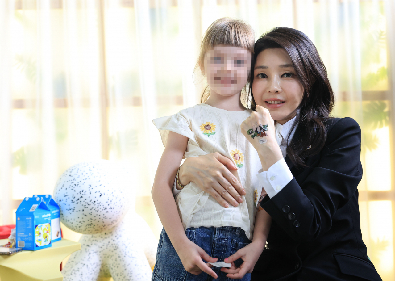 First lady Kim Keon Hee, who made a surprise visit to Ukraine with President Yoon Suk Yeol, visited the Child Rights Protection Center in Kyiv along with first lady Olena Zelenska and receives a dog-patterned sticker from a Ukrainian child who was forcibly repatriated to Russia and returned home. (Yonhap)