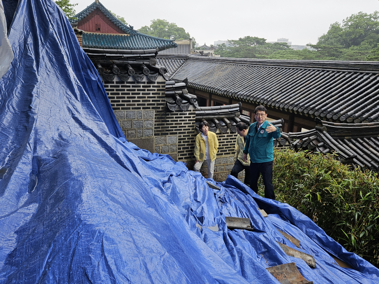 Choi Eung-chon, chief of CHA, checks on the damaged walls at Changdeokgung covered by a tarpaulin on Saturday. (Cultural Heritage Administration)