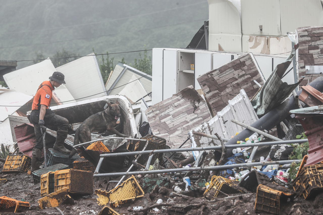 Rescue workers on Sunday search the site of a landslide in Yecheon-gun, North Gyeongsang Province, that buried five houses and left at least three dead and two missing. (Yonhap)
