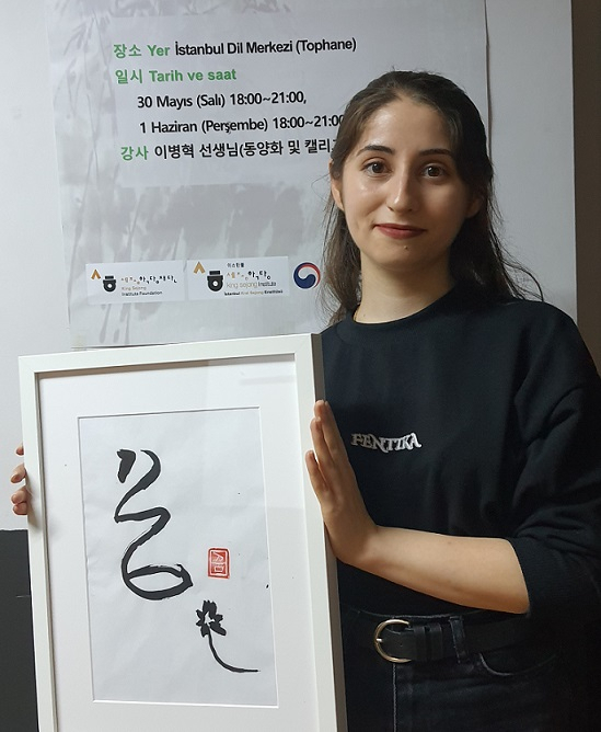 Gulperi Kucukkaraca holds her artwork of the Korean word for 