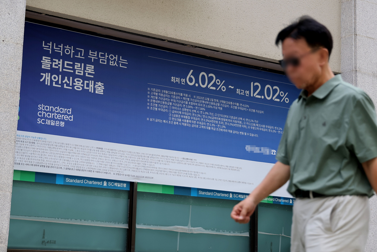 A man walks past street banner advertisement at a bank in Seoul that shows loan interest rates on June 25. (Yonhap)