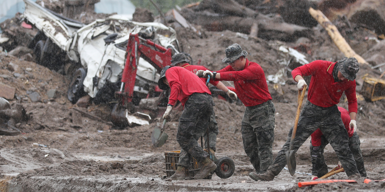 First Marine Division soldiers work to remove debris after a landslide as heavy rain pelts down in Gamcheon-myeon, Yechon in North Gyeongsang Province on Tuesday. (Yonhap)