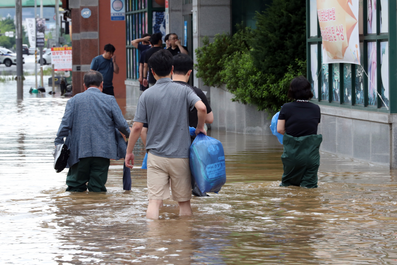 People wade through streets flooded by heavy rain in the city of Mokpo, South Jeolla Province, Monday. (Yonhap)