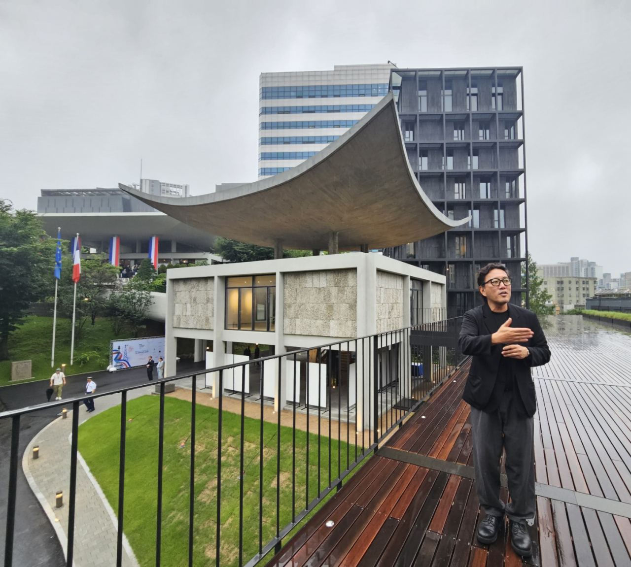 Architect Cho Min-suk speaks to the press on July 14 about the renovated French Embassy building located in Chungjeongno, central Seoul. The renovated building, “Le Pavilion Kim Chung-up,” and new Tour Monclar are seen behind Cho. (Park Yuna/The Korea Herald)