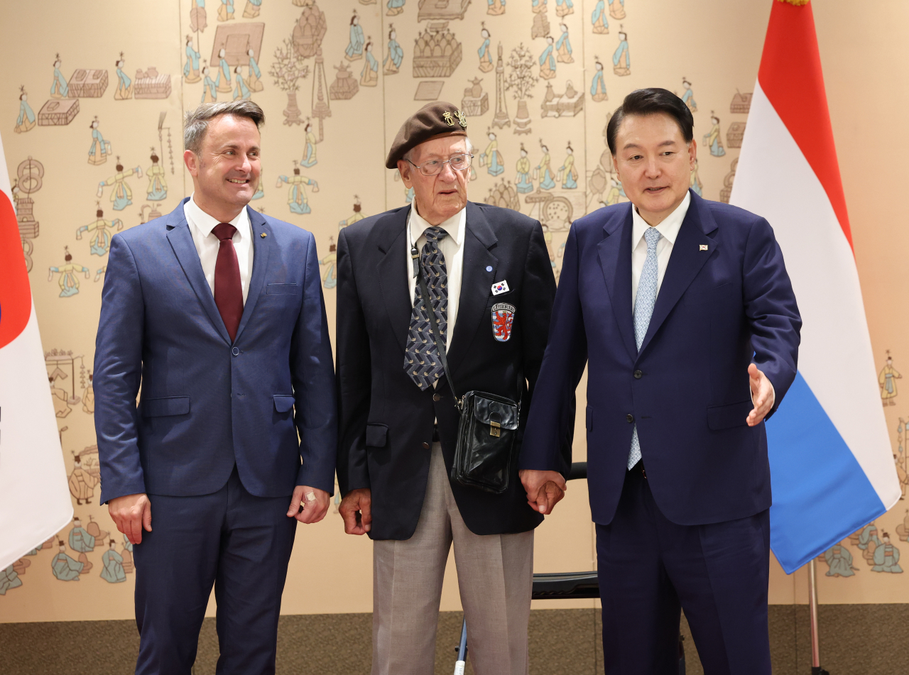 South Korean President Yoon Suk Yeol (right) guides Leon Moyen (center), a Luxembourgish Korean War veteran, after taking a photo at the presidential office in Seoul on Tuesday. On the left is Luxembourg Prime Minister Xavier Bettel. (Yonhap)
