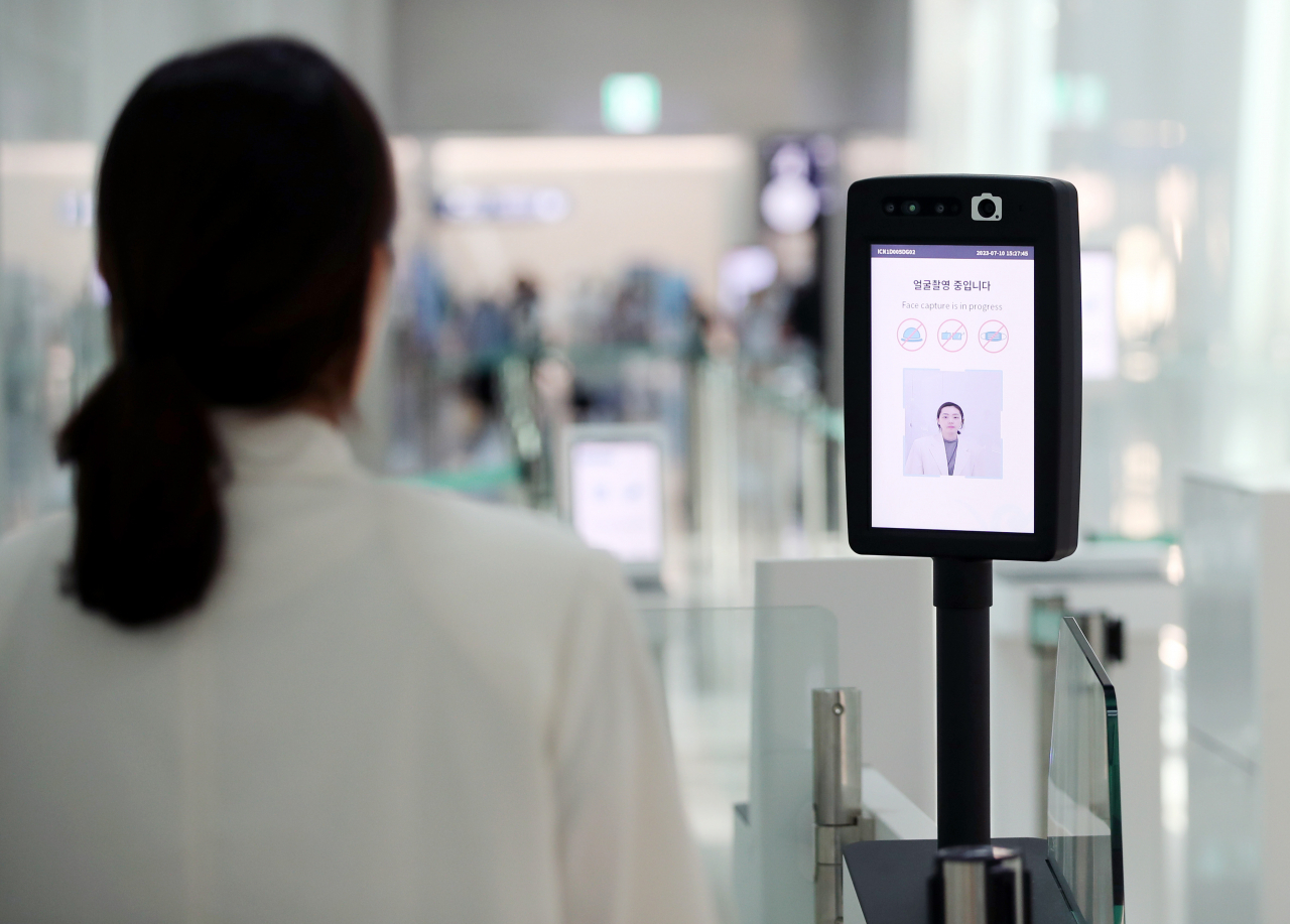 An employee of Incheon Airport demonstrates the uses of the facial recognition smart pass service installed at a departure gate of Terminal 1, Incheon Airport, on July 10. (Newsis)