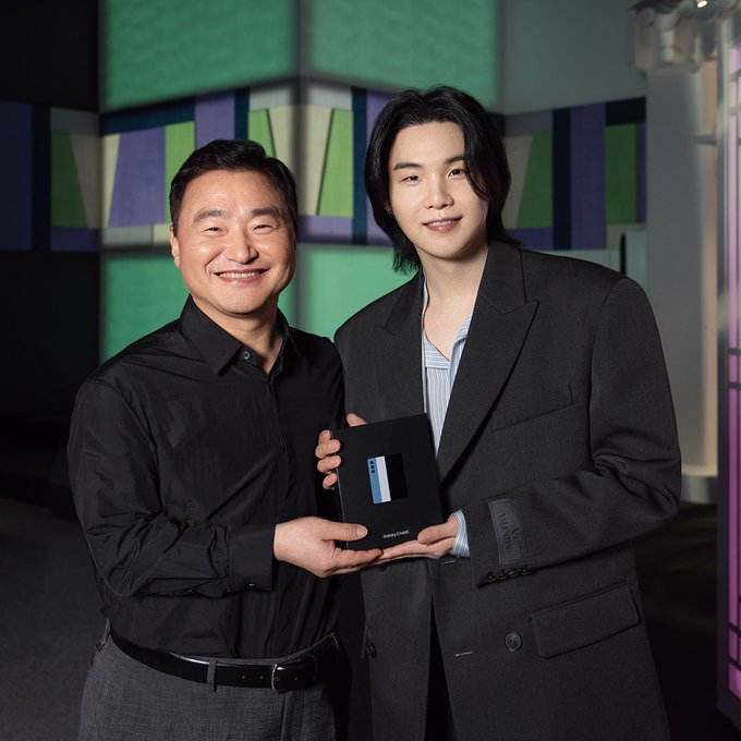 BTS' Suga (right) and Samsung Electronics' mobile chief Roh Tae-moon pose for a photo with the tech giant's new foldable smartphone. (Samsung Mobile Twitter)