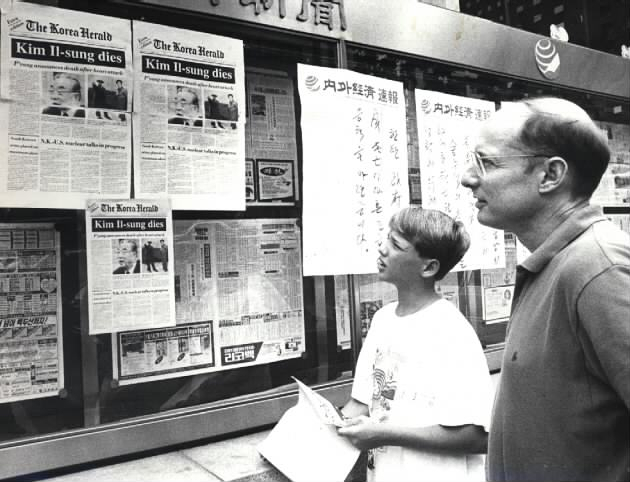 Two foreign nationals read an extra issue of The Korea Herald containing the news of North Korean founder Kim Il-sung's death in this file photo taken on July 9, 1994. (The Korea Herald DB)