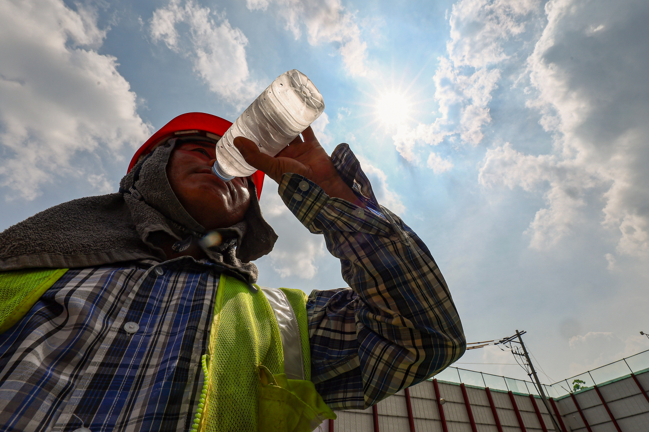 A worker drinks water at a construction site in downtown Seoul on Tuesday afternoon, when the midday temperature in Seoul soared to 35 degrees Celsius with the heat wave advisory issued in the most part of the country. (Yonhap)