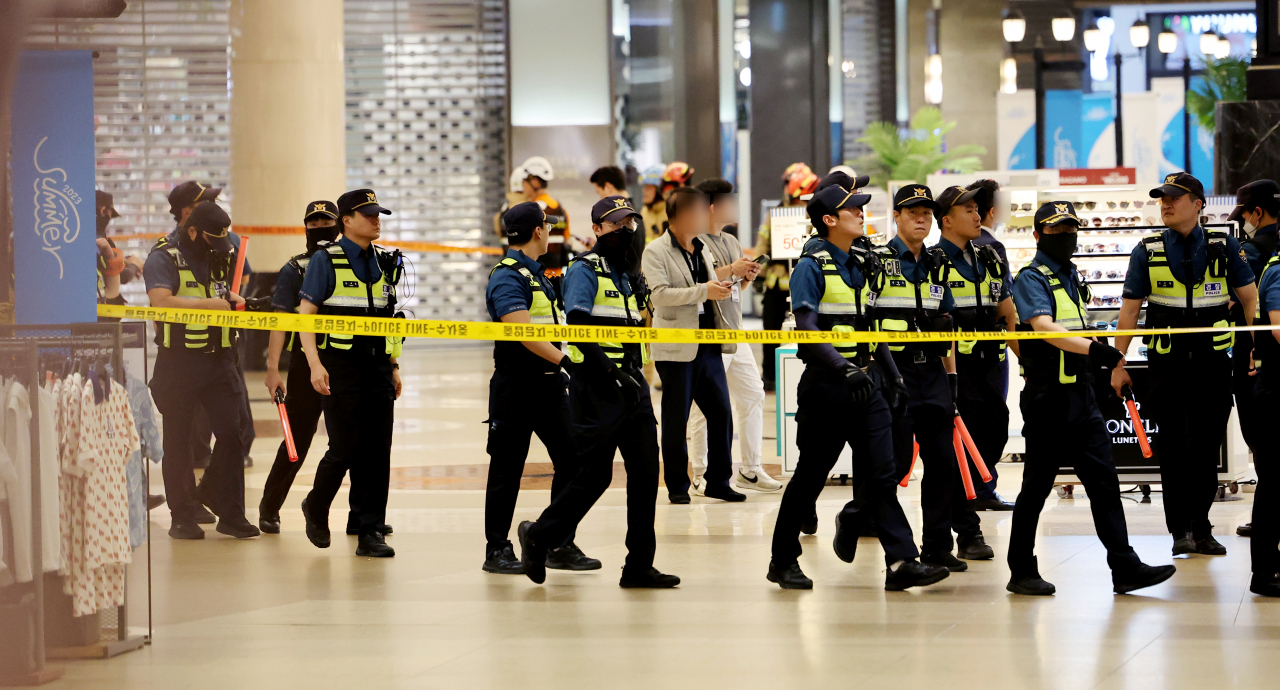 Police walk through the site of a stabbing rampage incident in a department store in Bundang, Gyeonggi Province on Thursday. (Yonhap)