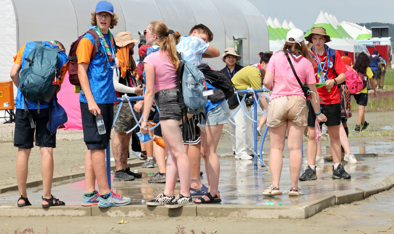Participants of the World Scout Jamboree gather at tap water facilities at a campsite at Saemangeum, a reclaimed land area on the southwestern coast, on Aug. 4, 2023. (Yonhap)