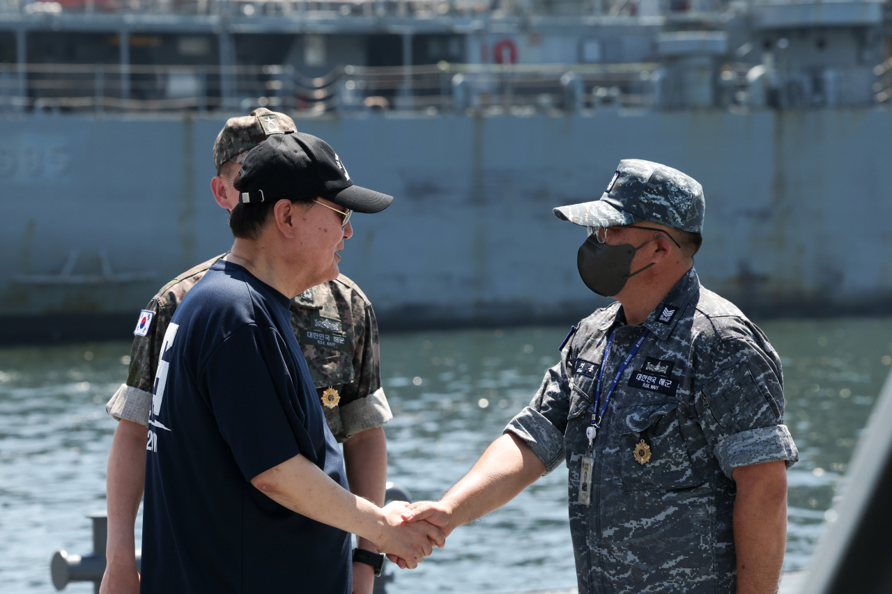 President Yoon Suk Yeol (left) shakes hands with a naval officer during a visit to a naval base in Jinhae, 311 kilometers southeast of Seoul, last Thursday, taking time out of his weeklong summer vacation. (Presidential office)