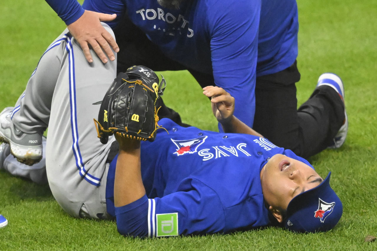 Ryu Hyun-jin of the Toronto Blue Jays is attended to by a team trainer after taking a line drive off his right knee during the bottom of the fourth inning of a Major League Baseball regular season game against the Cleveland Guardians at Progressive Field in Cleveland on Monday. (Reuters)