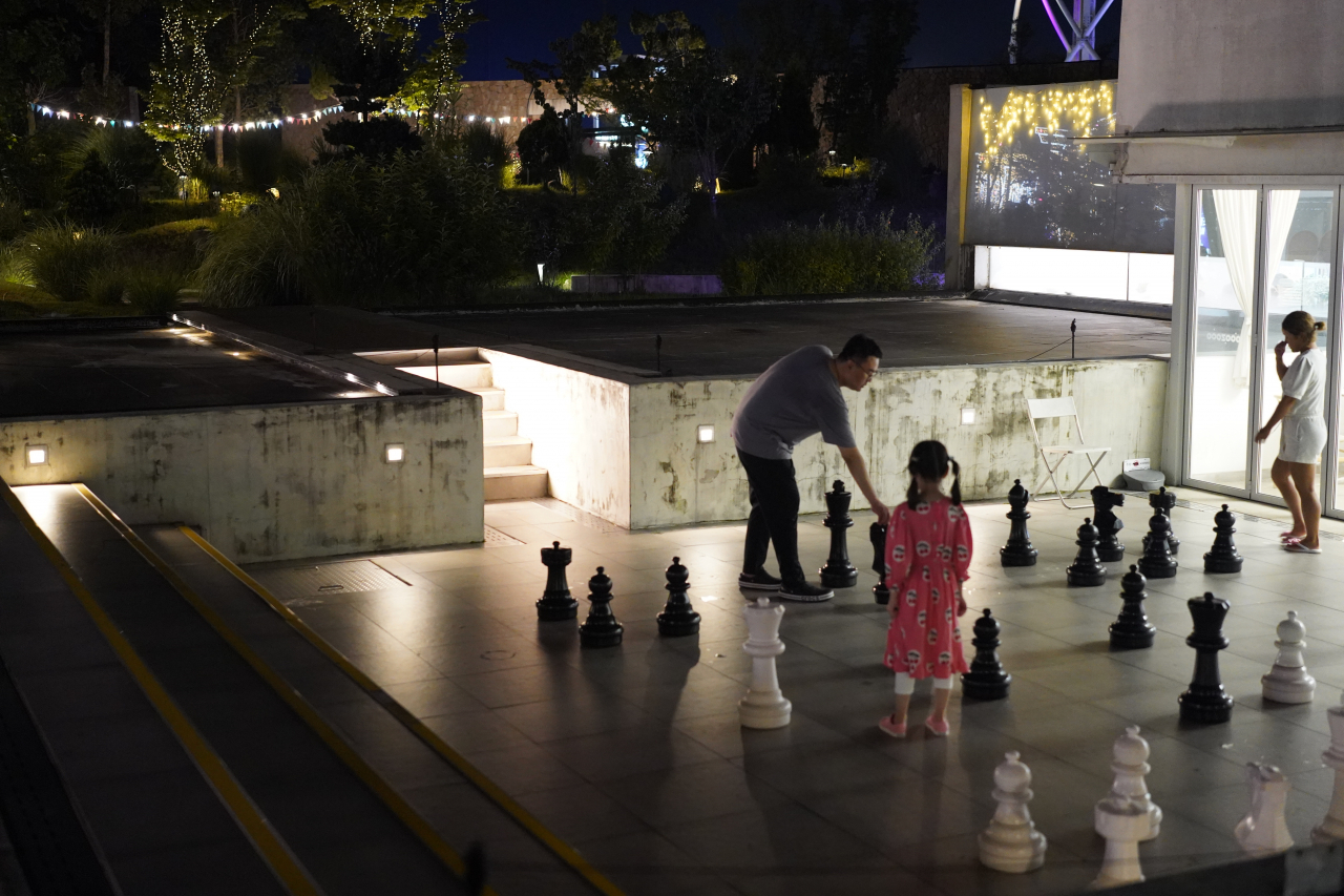 Father and daughter play a giant chess game at Deokpyeong-Eco Service Area in Icheon, Gyeonggi Province, on July 27. (Lee Si-jin/The Korea Herald)