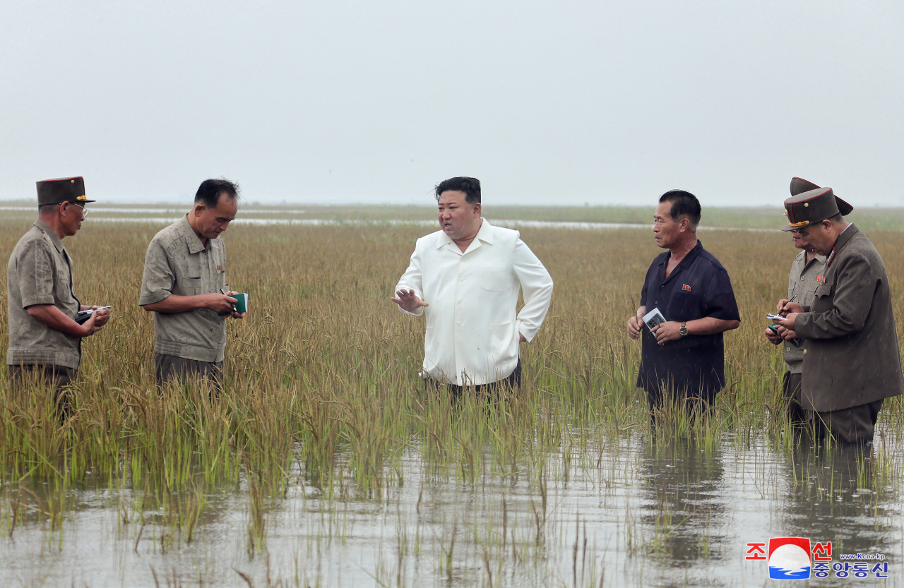 This photo, released by North Korea's official Korean Central News Agency on Tuesday, shows North Korean leader Kim Jong-un (in white shirt) inspecting a reclaimed area in South Pyongan Province the previous day, inundated by water after dikes collapsed due to a poor drainage system. (Yonhap)