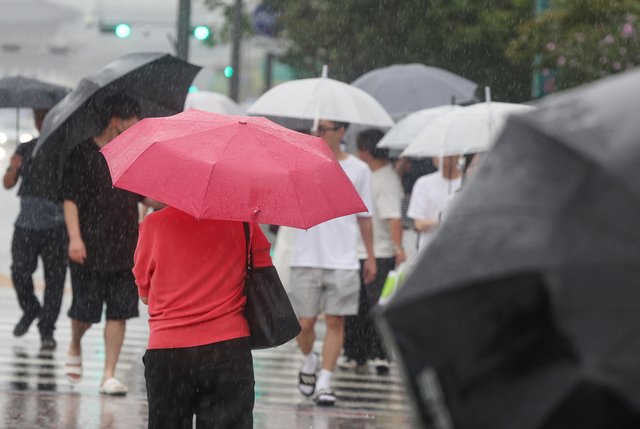 People holding umbrellas walk in a crosswalk in Jung-gu, Seoul, Wednesday. (Yonhap)