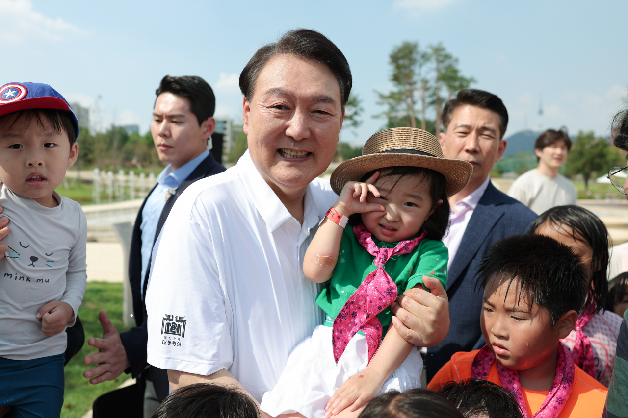 President Yoon Suk Yeol (center) poses with children during an event held for families with multiple children at Yongsan Children's Garden, near the presidential office, in Seoul on Saturday. (Yonhap)