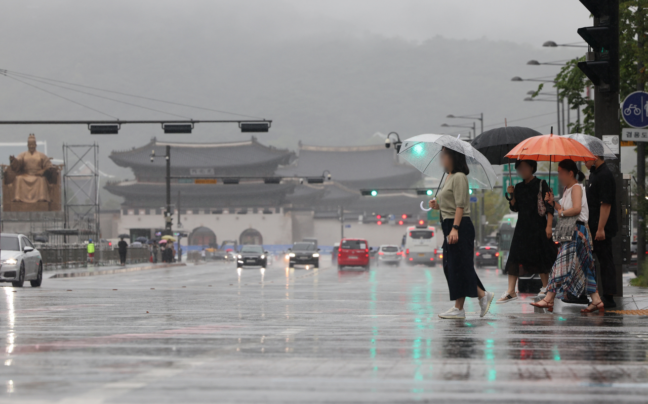 Citizens cross the road in the rain in Jung-gu, central Seoul, Aug. 23. (Yonhap)