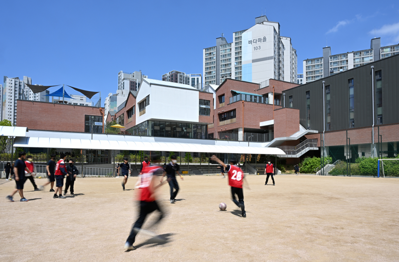Kids play soccer on a field at Singil Middle School. The school is located amid the high-rise apartment buildings of Singil-dong in Seoul. (Im Se-jun/The Korea Herald)
