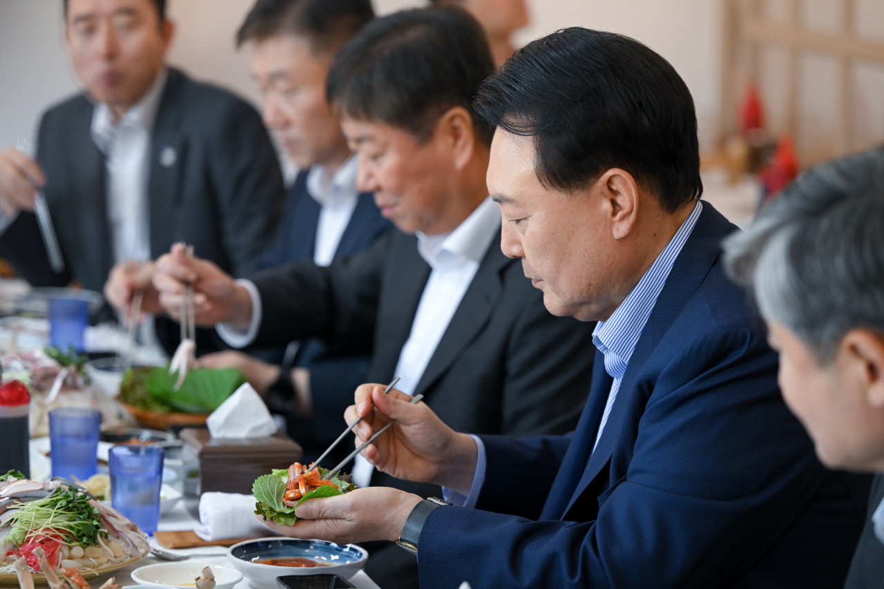 President Yoon Suk Yeol (R) eats seafood for lunch during a visit to the Noryangjin fish market in Seoul, on Thursday, in this photo provided by the presidential office.