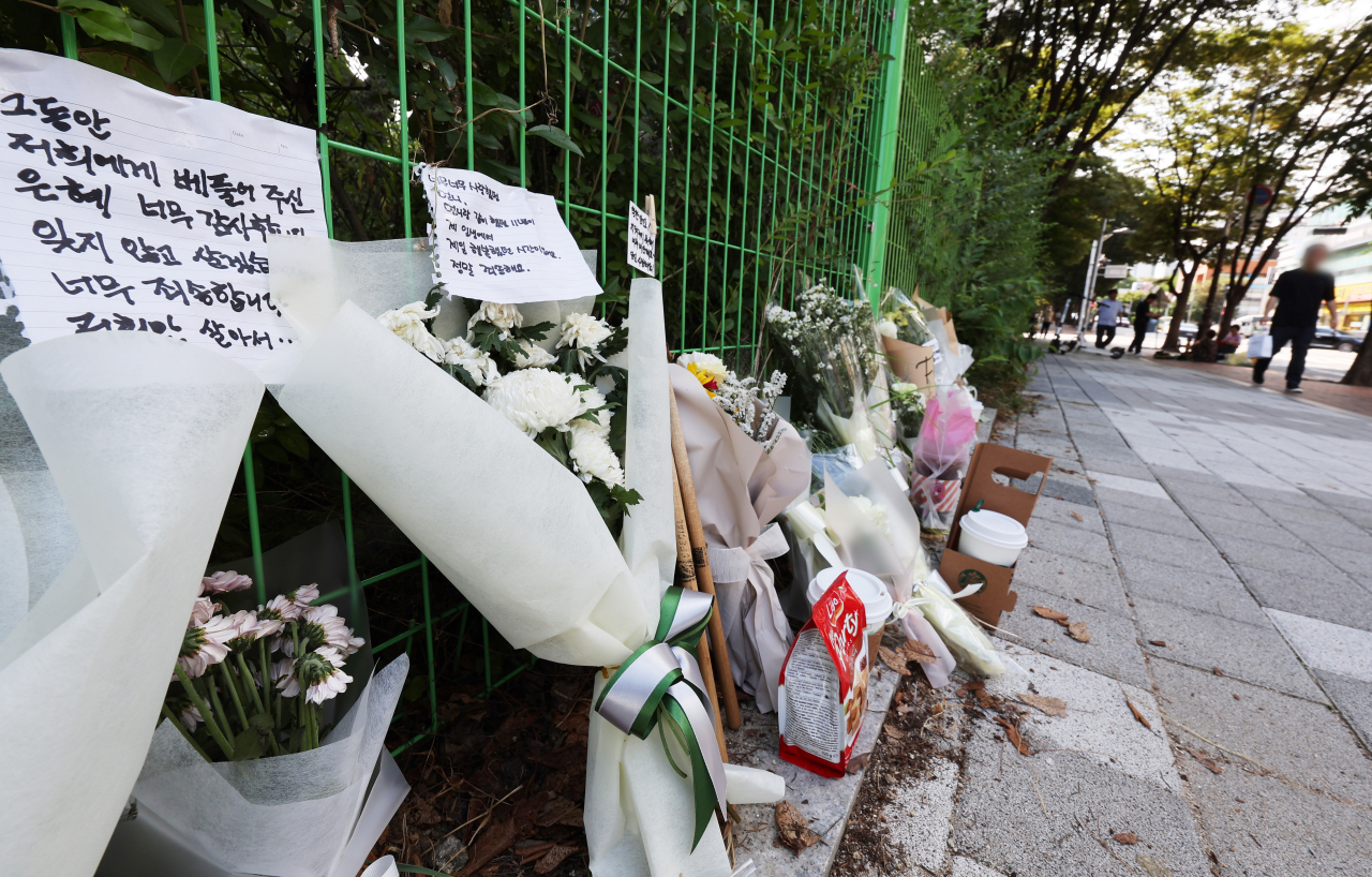 Flowers and letters paying tribute to those who lost their lives in the Aug. 3 stabbing rampage are lain at the scene of the crime, near a department store at Seohyeon Station in Bunsdang, Gyeonggi Province. (Yonhap)