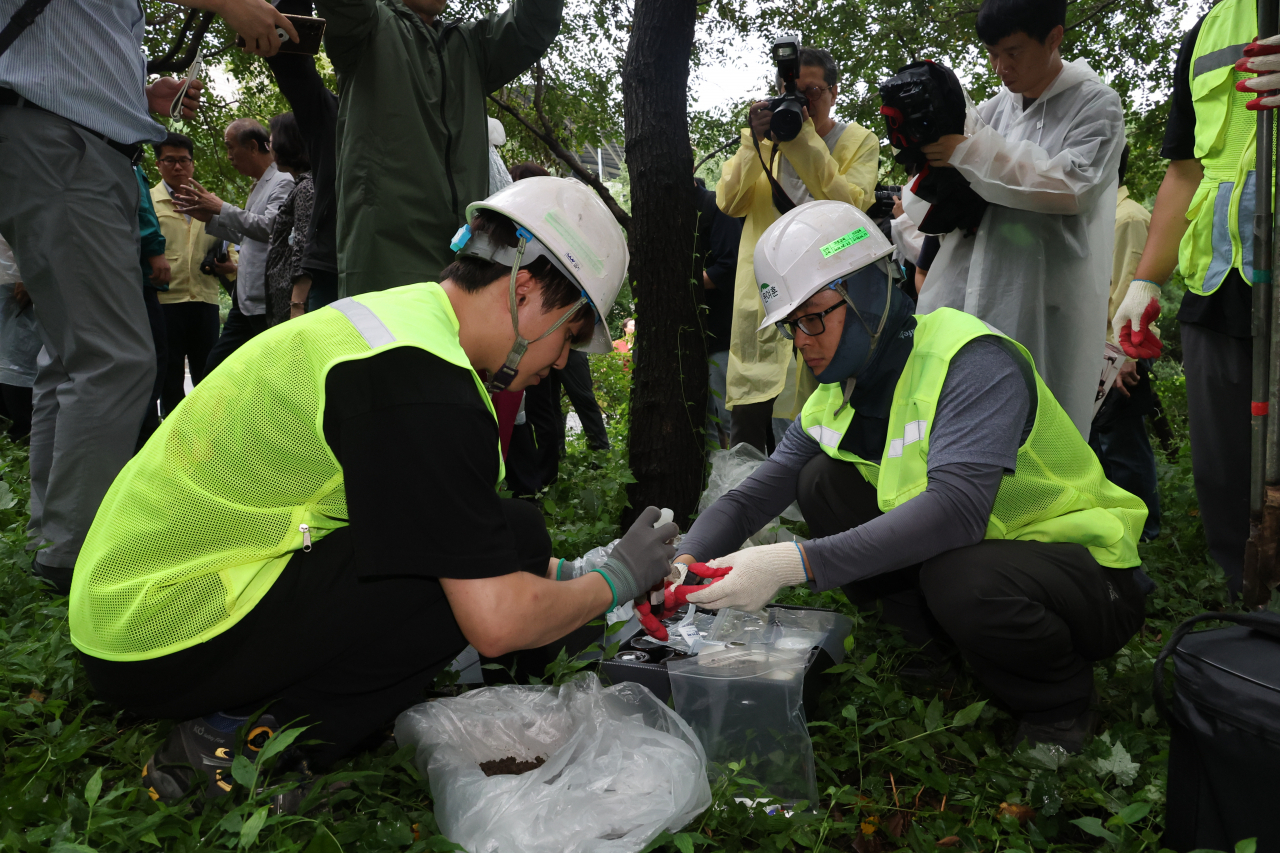 Soil pollution investigative agency officials take a sample of soil at the proposed site of a new waste incineration plant in Mapo-gu, western Seoul on Aug. 28. (Yonhap)